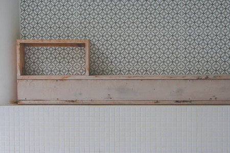 Front view of empty wooden shelf above over the bathtub with black and grey geometric circle in the background.の写真素材
