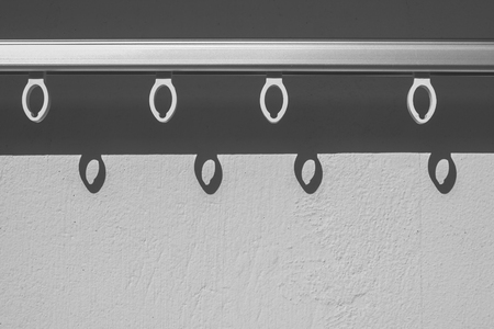 Abstract black and white image of hole hanging on clothes line with shadow on the concrete wall at outdoor. (Soft focus)の写真素材