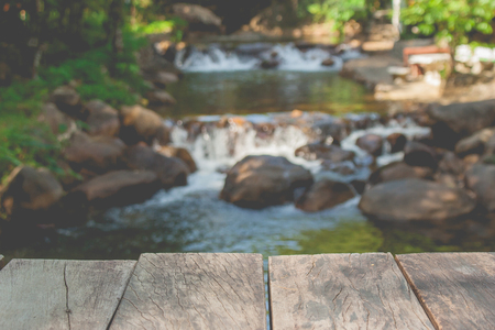 Close up wooden floor of bridge with beautiful landscape view of small waterfall in the river with water stream flowing through stone in the background. (Selective focus)の写真素材