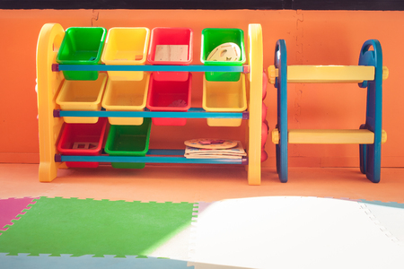 Close up colorful plastic shelf and toy boxs in kids room with orange color background in vintage style. (Selective focus)の写真素材