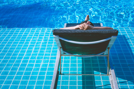 Relaxation Concept : Woman sleeping on outdoor daybed in swimming pool at the resort.の写真素材