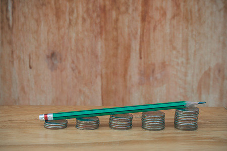 Business Creative and Idea Concept : Used green pencil on stack of silver coins (Baht) put on wooden table (Selective focus)の写真素材