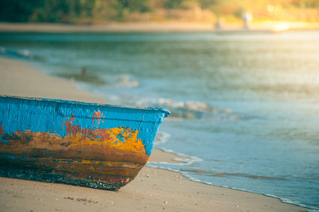 Colorful wooden fishing boat on sand beach with sea wave in the background in vintage style. (Soft focus)の写真素材