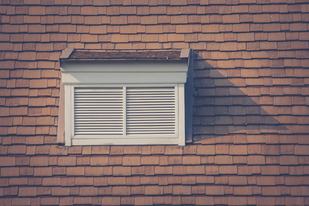 Front view of white wooden window on rooftop of wooden house in vintage style at countryside. (Selective focus)の写真素材