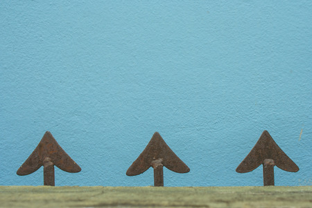 Close up head arrow shape of cast iron fence or metal fence with blue concrete wall in the...