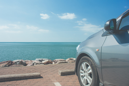 Car parked on parking lot at seashore near the beach with seascape and blue sky in the background.の写真素材