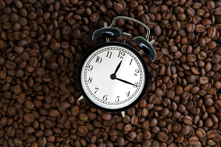 Coffee Break Concept : Top view retro black alarm clock lie on coffee beans.の写真素材