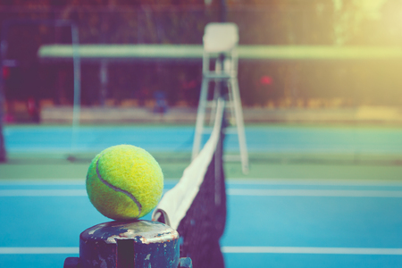 Green ball place on net pole and black net of outdoor blue tennis hard court in public park. (Selective focus)の写真素材