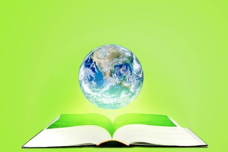Ecology and Education Concept : Planet earth globe floating over opened book with green background.の写真素材