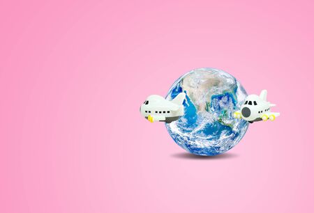 Traveling and Vacation Concept : Airplane flying around blue planet earth globe with pink background.の写真素材