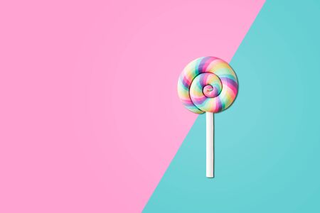 Colorful sweet swirl lollipop on half pink and blue color background.の写真素材