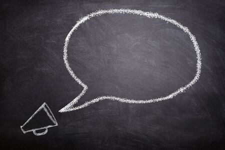 Business Communication Concept : White megaphone and speech bubble on chalkboard.の写真素材