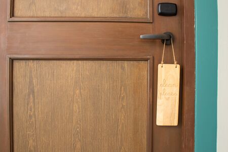 Please clean room message on wooden label hanging on door knob in front of room at the hotel.の写真素材