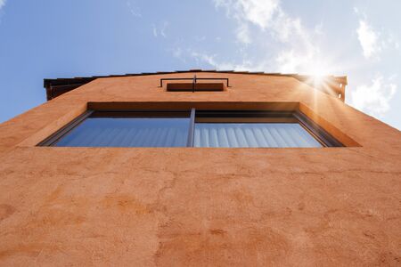 Uprisen angle view of resident with orange clay wall and blue sky in background.の写真素材