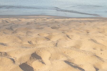 Tropical brown sand beach and blue sea in background.