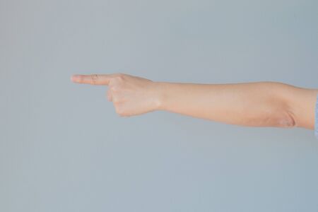 Hand of female gesturing in single pointing finger shape with gray background.の写真素材