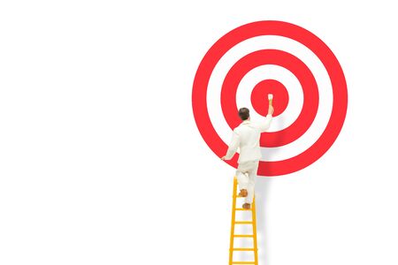 Business and Marketing Concept : Miniature as painter stand on ladder and painting red dartboard.の写真素材