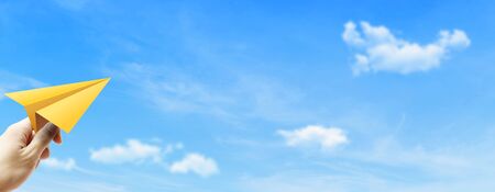Freedom Concept : Hand holding yellow paper plane and throwing to blue sky.の写真素材
