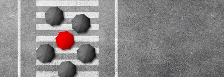 Aerial view of Red umbrella in mass of black umbrellas on white pedestrian crosswalk or Zebra...