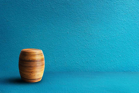 Wooden round weave chair in blue concrete room.