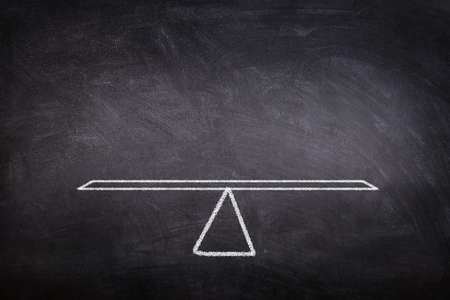 Business Concept : White chalk drawing seesaw or balance scale on blackboard.