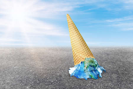 Global Warming and Pollution Concept : Ice cream planet earth melting on asphalt road with blue sky and sunlight in background.の写真素材