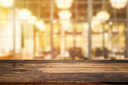 Empty wooden table with abstract blurry image of coffee shop or cafe restaurant in background for product showing and advertising.の写真素材