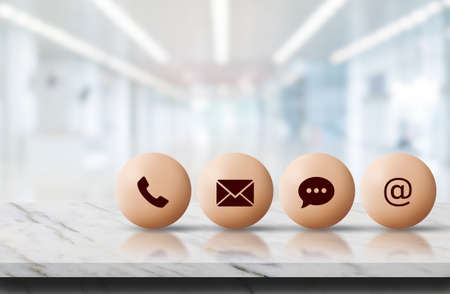 Call Center and Contact US Concept : Contact icon symbols put on marble stone table top with blurry...