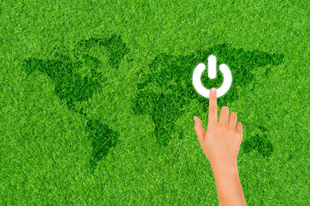 Earth Hour, Ecology and Environment Concept : Finger hand press on white electric power button icon on green grass for Earth Hour Event.の写真素材