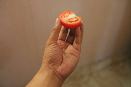 Half slice tomato on top of the man fingerの写真素材