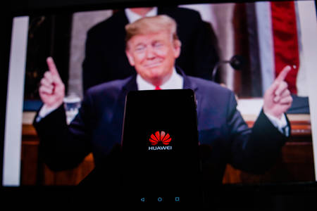 PERAK, MALAYSIA - MAY 24, 2019: A man holds an android-smartphone that shows the logo for the google play store in front of the picture of Donald Trump. Google is restricting Huawei's access to its Android system.のeditorial素材