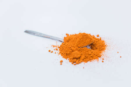 Curry powder in the top of the spoon isolated on white background