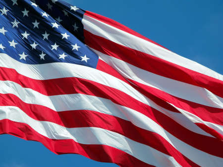Waving American Flag against a blue sky background.