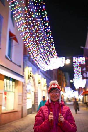Happy and cheerful Vietnamese girl walks around shopping streets in a winter evening.の写真素材