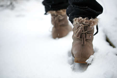 Girl walking on the snow with boots in the afternoonの写真素材