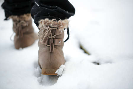 Girl walking on the snow with boots in the afternoonの写真素材
