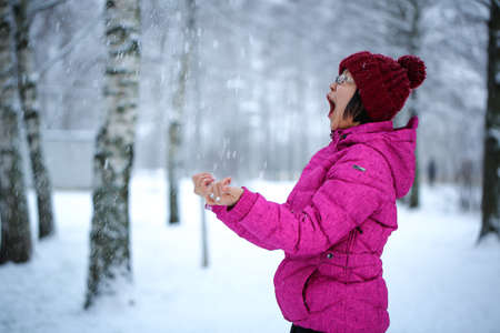 Young and happy asian girl with a pink jacket enjoys snowingの写真素材