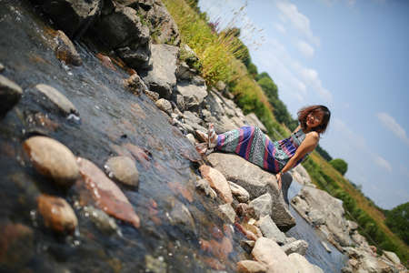 Young asian girl in a colorful maxi dress playing by a river in the summerの写真素材