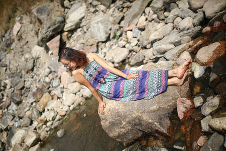 Young asian girl in a colorful maxi dress playing by a river in the summerの写真素材