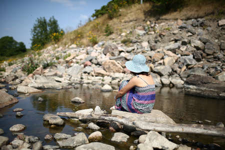 Young asian girl in a colorful maxi dress playing by a river in the summerの写真素材