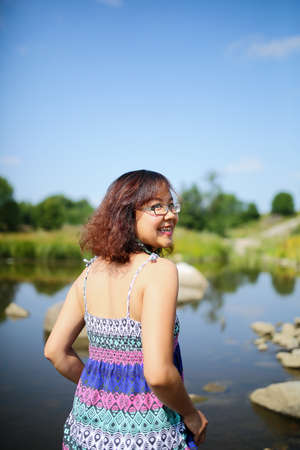 Young asian girl in a colorful maxi dress playing by a river in the summerの写真素材