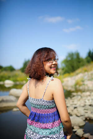 Young asian girl in a colorful maxi dress playing by a river in the summerの写真素材