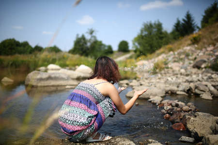 Young asian girl in a colorful maxi dress playing by a river in the summerの写真素材