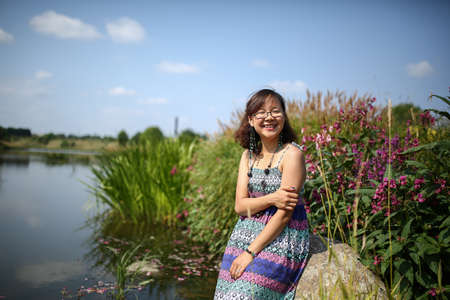 Young asian girl in a colorful maxi dress playing by a river in the summerの写真素材