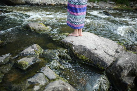 Young asian girl in a colorful maxi dress playing by a river in the summerの写真素材