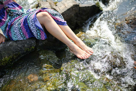 Young asian girl in a colorful maxi dress playing by a river in the summer