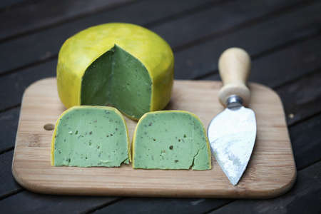 Dutch pesto cheese slices on a wooden background in a closeup view.の写真素材