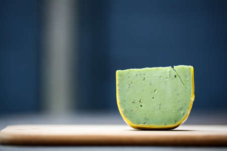 Dutch pesto cheese slices on a wooden background in a closeup view.の写真素材