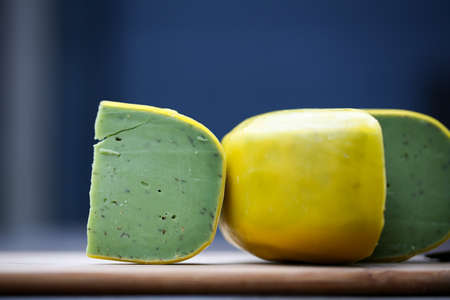 Dutch pesto cheese slices on a wooden background in a closeup view.の写真素材