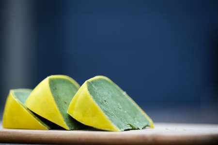 Dutch pesto cheese slices on a wooden background in a closeup view.の写真素材